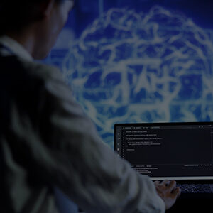 Person working on a laptop with programming code displayed on screen